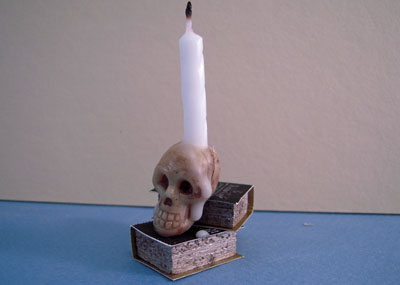 1" scale skull candle on books